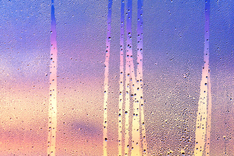 Texture of water drops on glass with magenta sunset on backgroun